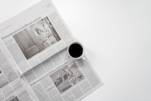 coffee cup sitting on top of an open newspaper