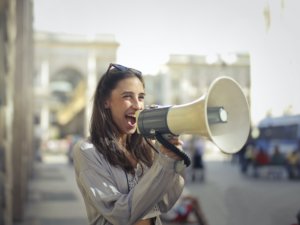a happy young woman shouting into a megaphone